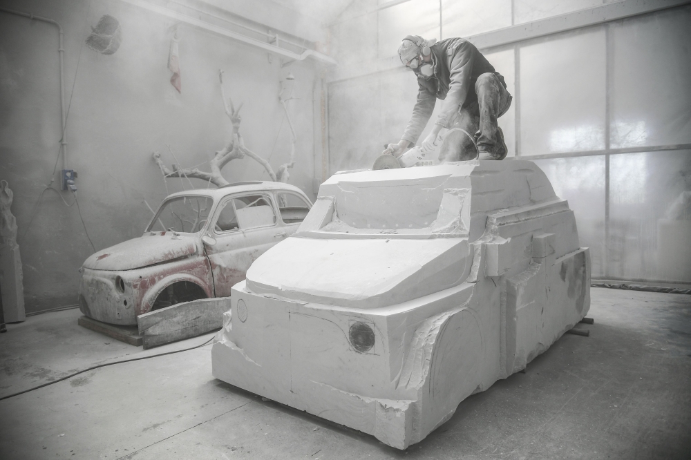 Italian artist Nazareno Biondo works a sculpture made with Carrara's marble representing the iconic car Fiat 500, on May 16, 2018 in Cafasse, near Turin. AFP / MARCO BERTORELLO 