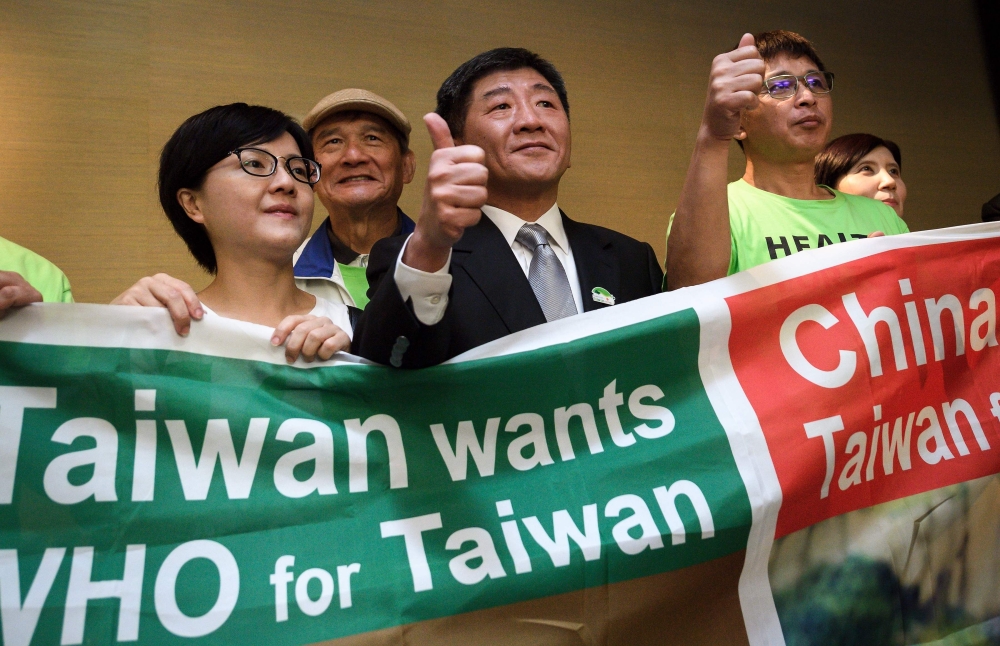 Taiwan's Health Minister Chen Shih-Chung (C) gives a thumb up as he poses with demonstrators after a press conference on the sideline of the World Health Assembly on May 21, 2018 in Geneva. AFP / Fabrice Coffrini 