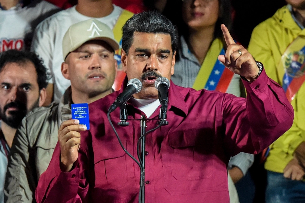 Venezuelan President Nicolas Maduro holds the political constitution after the National Electoral Council (CNE) announced the results of the voting on presidential election, on May 20, 2018, in Caracas, Venezuela.   AFP / Juan BARRETO
