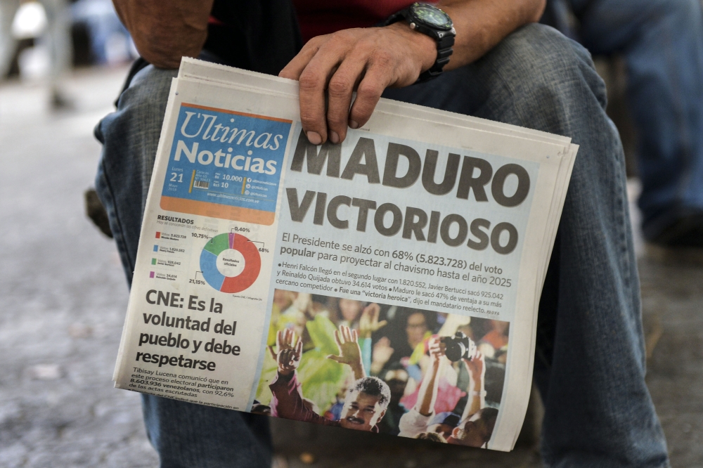 A man holds a newspaper referring to the victory of re-elected President Nicolas Maduro in the Venezuelan presidential election in Caracas, on May 21, 2018. AFP / Luis ROBAYO
