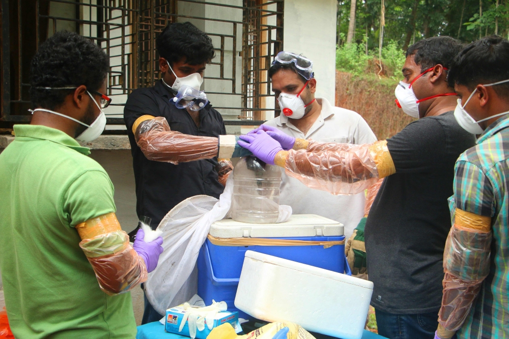 Animal Husbandry department and Forest officials deposit a bat into a container after catching it inside a well at Changaroth in Kozhikode in the Indian state of Kerala on May 21, 2018. (AFP) 
