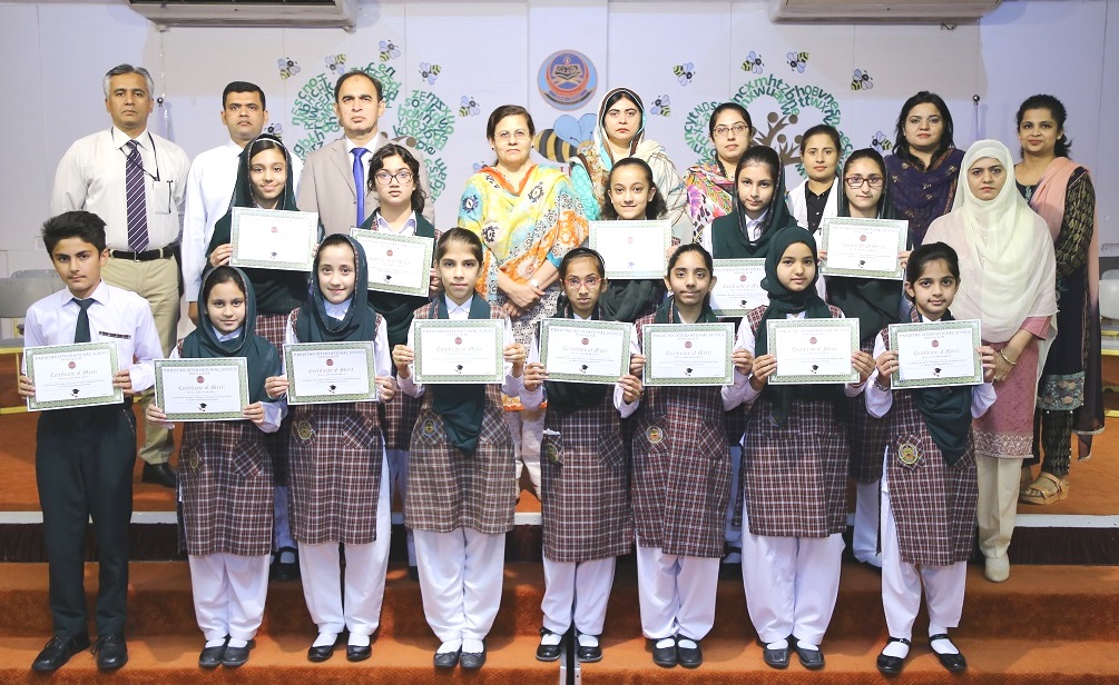 Students, who won the spelling bee competition, hold certificates with the staff of PISQ. 