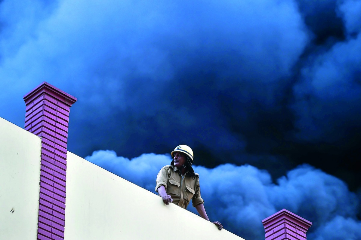 A firefighter works to douse the fire inside a warehouse caused by a truck in New Delhi on May 29, 2018.  AFP / Chandan Khanna