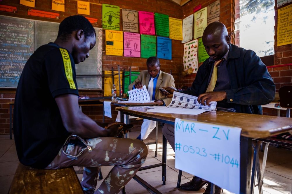 A prospective voter (L) checks her voter registration details with ZEC officials on May 29 2018 at an inspection centre in Harare, ahead of Zimbabwe harmonised 2018 general election, expected for July. AFP / Jekesai NJIKIZANA