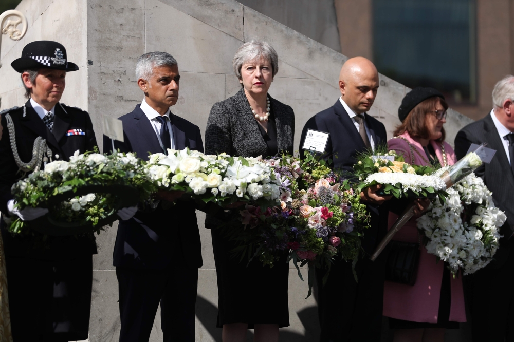 Mayor of London Sadiq Khan, (2L), Britain's Prime Minister Theresa May, (C) and Britain's Home Secretary Sajid Javid (2R) hold floral tributes during a commemoration service on the first anniversary of the London Bridge terror attack, at Southwark Needle 