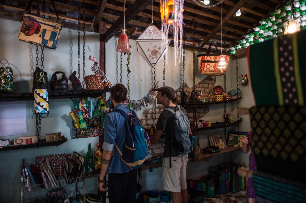 Two tourists look at crafts made out of recycled materials in a Chu Chu recycling shop in Dala, on the outskirts of Yangon, on June 4, 2018. AFP / Ye Aung THU