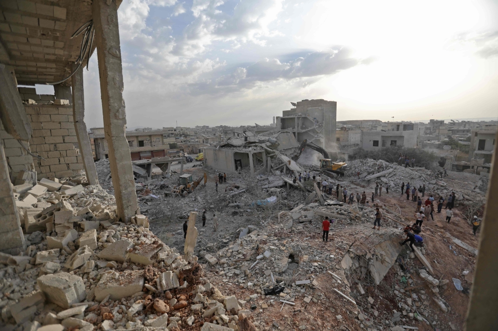 Syrians gather amidst destruction in Zardana, in the mostly rebel-held northern Syrian Idlib province, in the aftermath of following air strikes in the area late on June 8, 2018.   AFP / OMAR HAJ KADOUR
