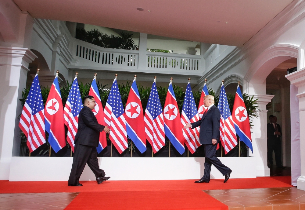 US President Donald Trump (R) and North Korea's leader Kim Jong Un (L) reach out to shake hands at the start of their historic US-North Korea summit, at the Capella Hotel on Sentosa island in Singapore on June 12, 2018. (Kevin Lim / The Straits Times / Ha