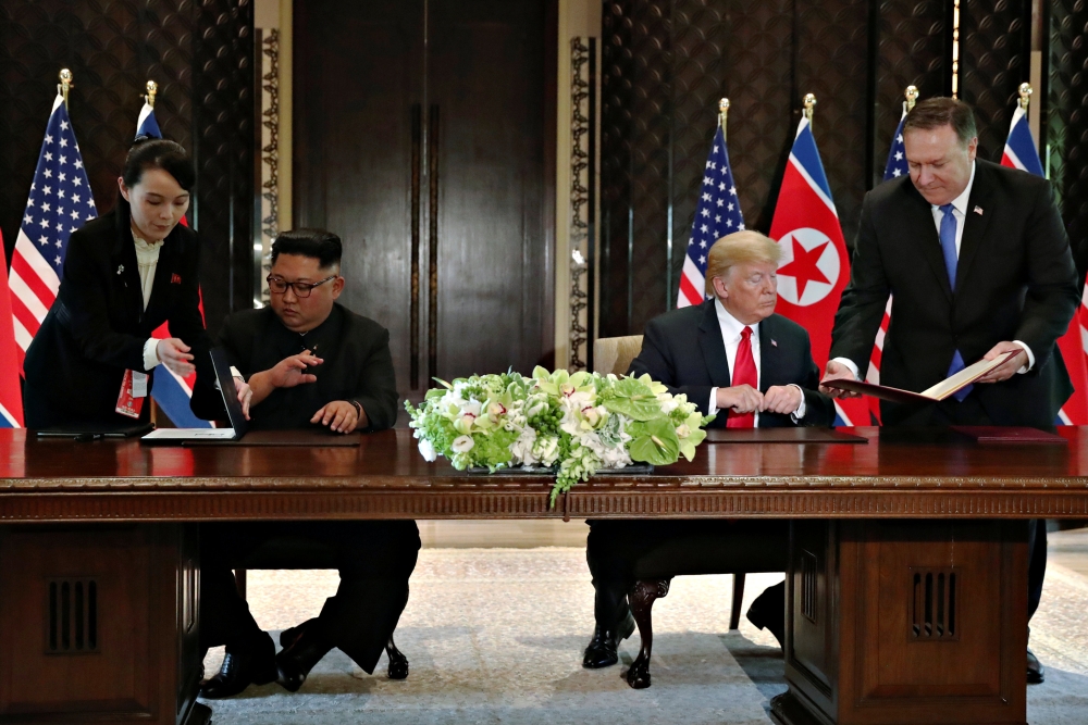 Kim Yo Jong shows a document to her brother, North Korea's leader Kim Jong Un as U.S. Secretary of State Mike Pompeo shows a copy of it to President Donald Trump before they sign them at their summit at the Capella Hotel on Sentosa island in Singapore Jun