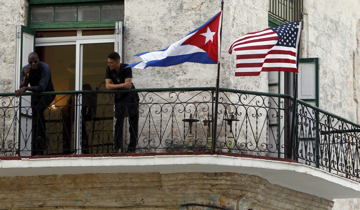 Two men stand on a balcony next to the Cuban and USA National Flags in Havana, Cuba, March  17,  2016. EPA / Ernesto Mastrascusa