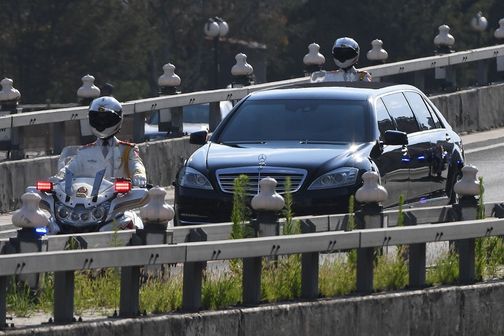 The car believed to be carrying North Korean leader Kim Jong Un is escorted by motorcycles in Beijing on June 19, 2018. / AFP / GREG BAKER 