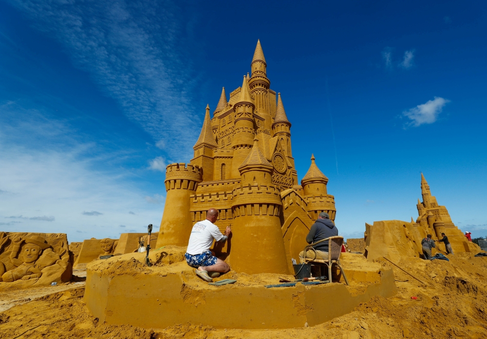 A sand carver works on a sculpture during the Sand Sculpture Festival 