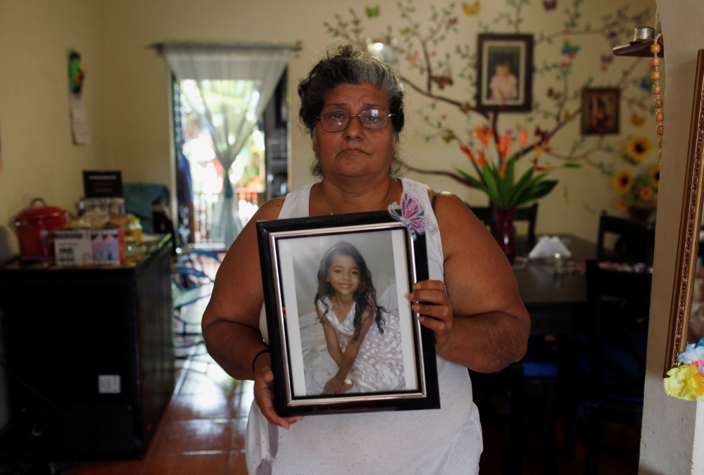 Ana Henriquez poses for a picture while holding a photograph of her granddaughter Alison Valencia, who was detained along with her mother and then separated when they arrived in the US in Armenia, El Salvador June 20, 2018. Reuters/Jose Cabezas
