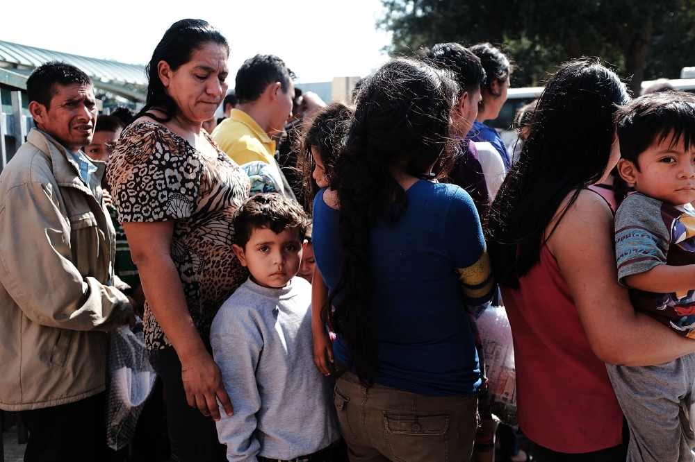 Dozens of women, men and their children, many fleeing poverty and violence in Honduras, Guatamala and El Salvador, arrive at a bus station following release from Customs and Border Protection on June 23, 2018 in McAllen, Texas.(Spencer Platt/Getty Images/