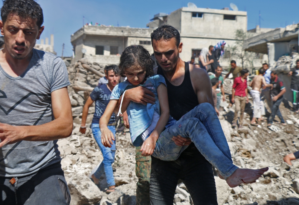 A man carries a child rescued from rubble after Syrian regime and Russian air strikes in the rebel-held town of Nawa, about 30 kilometres north of Daraa in southern Syria on June 26, 2018.  AFP / Ahmad al-Msalam
