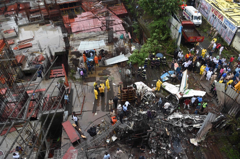 Indian rescue workers, firemen and investigators gather around the wreckage of a small plane that crashed into a construction site, killing five people, in Mumbai on June 28, 2018.