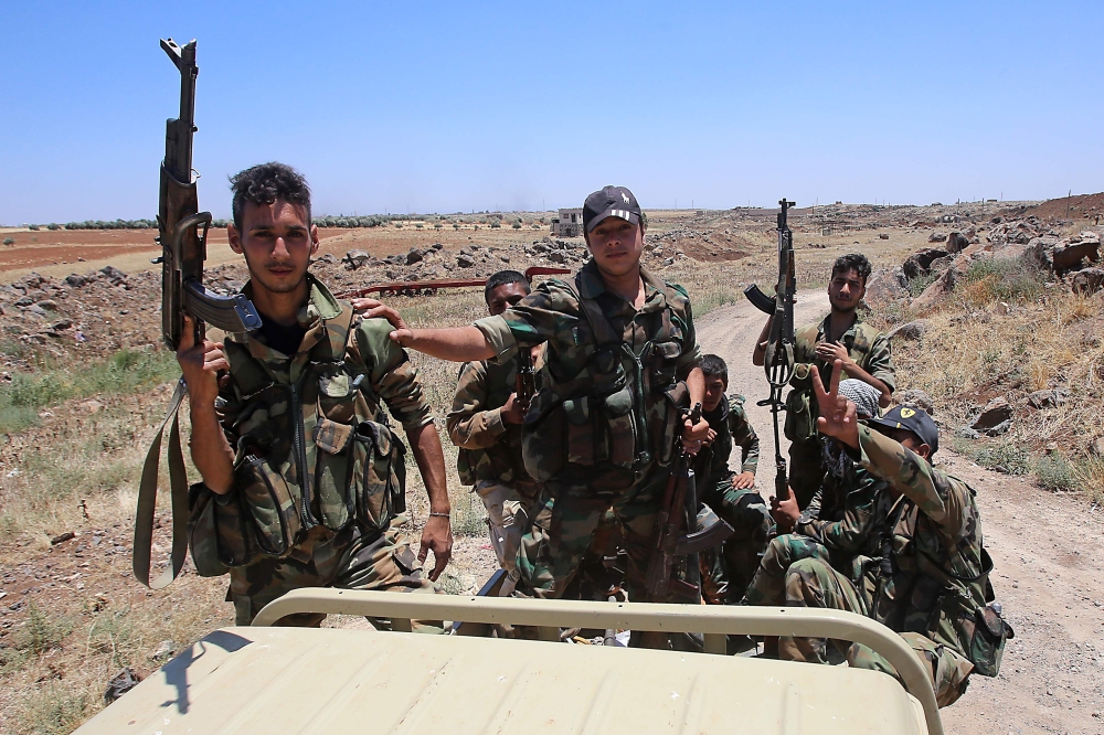 Syrian government forces' soldiers hold their weapons at the back of a pick-up truck during a government guided tour in the village of al-Sourah, province of Daraa, on June 29, 2018. AFP / Youssef Karwashan 