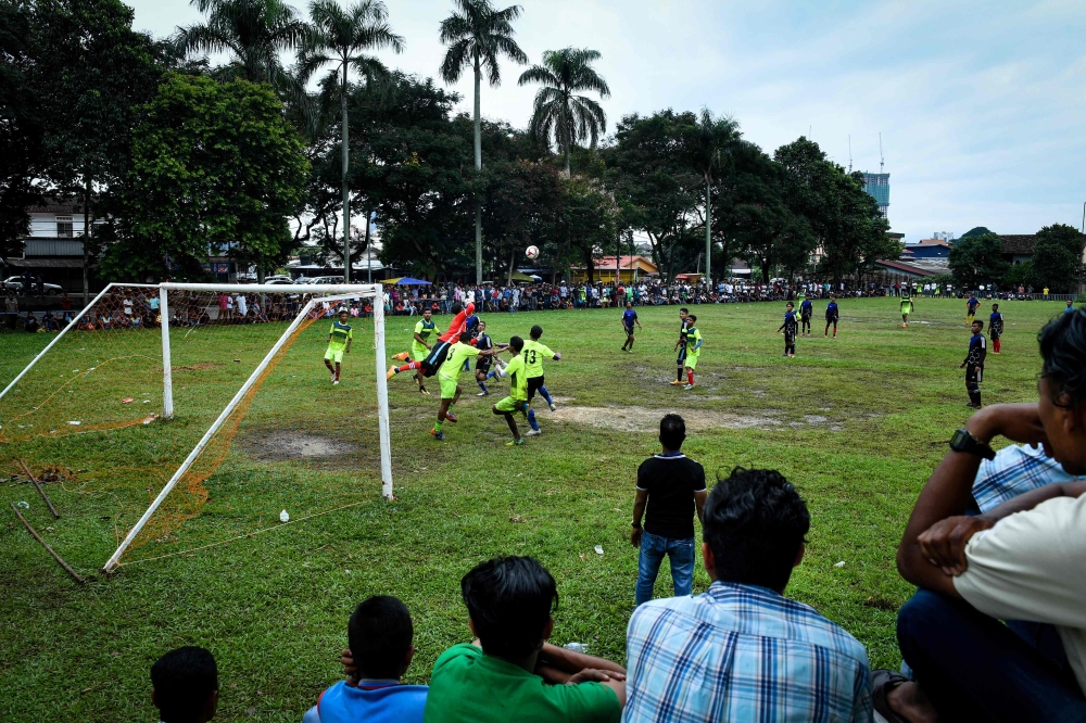 This picture taken on June 17, 2018 shows Rohingya residents watching Rohingya FC and Cheras Harimau teams play during a three-day tournament for refugees, marking the Eid al-Fitr Islamic festival, on the outskirts of Kuala Lumpur.  AFP / Lillian SUWANRUM
