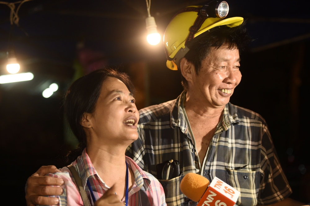 Family members celebrate while camping out near Than Luang cave following news all members of children's football team and their coach were alive in the cave at Khun Nam Nang Non Forest Park in the Mae Sai district of Chiang Rai province late July 2, 2018