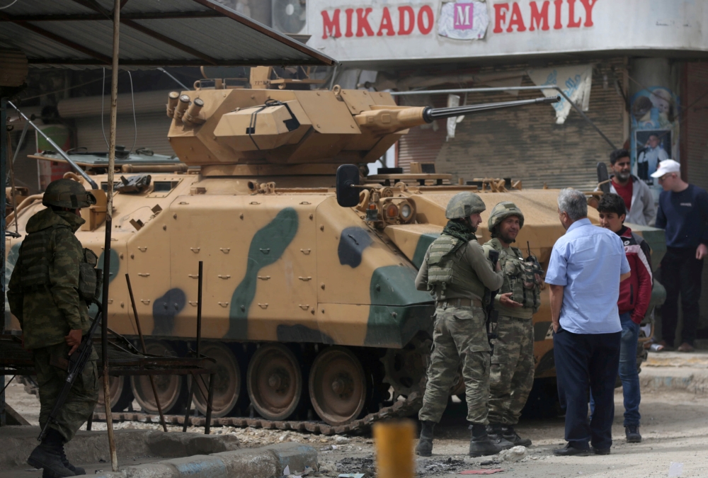 FILE PHOTO: People speak with Turkish soldiers in the center of Afrin, Syria March 24, 2018. REUTERS/Khalil Ashawi/File Photo