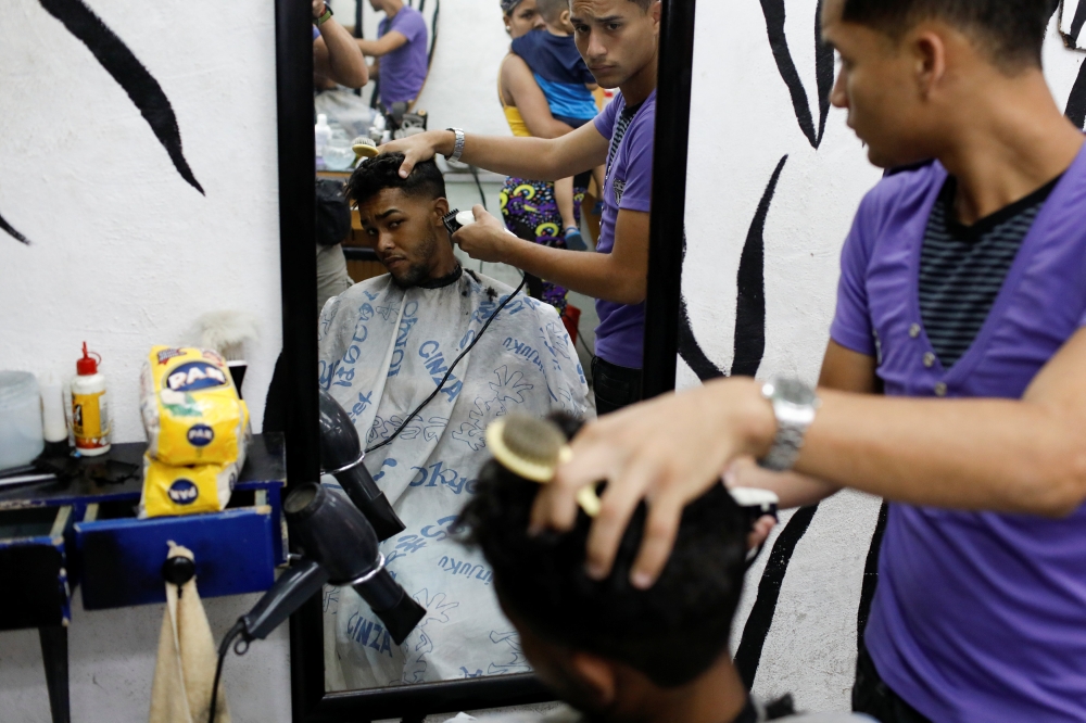 A man gets a haircut after paying for it with two packages of corn flour in Caracas, Venezuela June 29, 2018. Reuters/Marco Bello