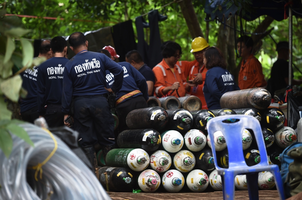 Thai rescue workers convene behind a large pile of oxygen tanks at the Tham Luang cave area as operations continue for the 12 boys and their coach trapped at the cave in Khun Nam Nang Non Forest Park in the Mae Sai district of Chiang Rai province on July 
