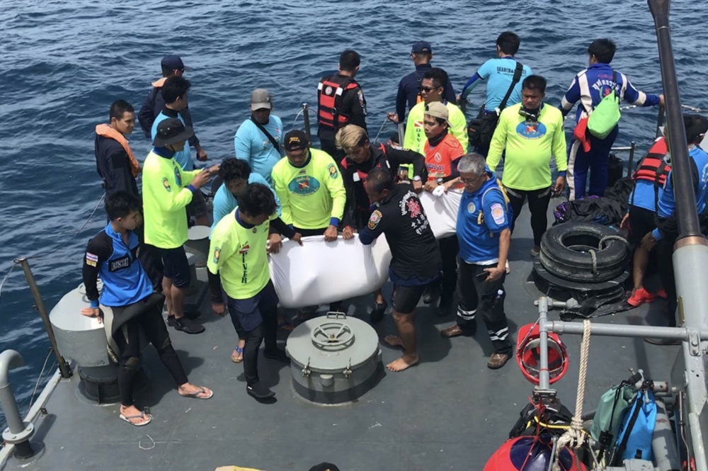 Thai rescue personnel aboard a search and rescue ship recover a body from a capsized tourist boat at sea off Phuket on July 6, 2018.  AFP / Sakorn Petchthong