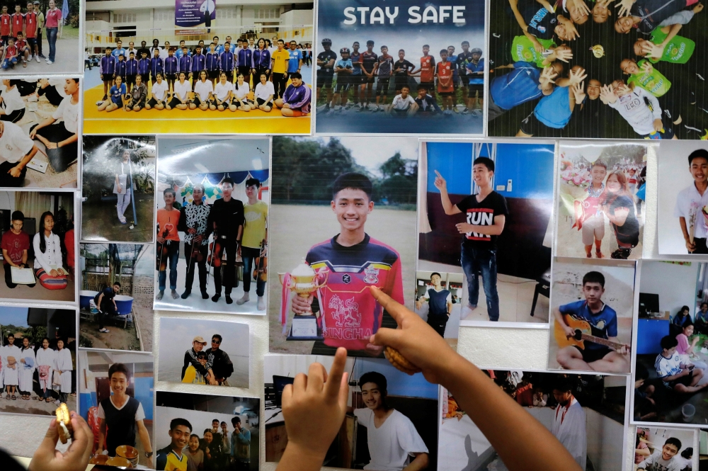 Children look at pictures of students before relatives and friends pray for the 12 schoolboys and their soccer coach trapped inside a flooded cave, at Mesai Grace Church in the northern province of Chiang Rai, Thailand, July 8, 2018. REUTERS/Soe Zeya