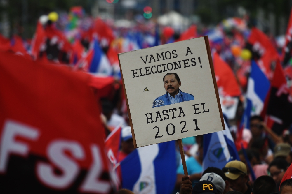 A supporter of embattled Nicaraguan President Daniel Ortega holds a placard reading 