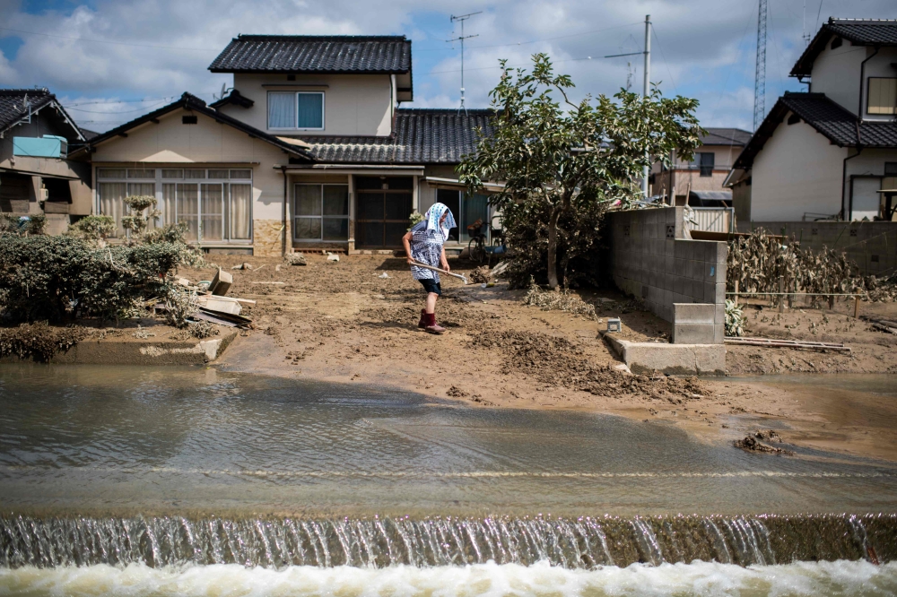 A woman removes mud from her damaged home in a flood hit area in Mabi, Okayama prefecture on July 10, 2018. AFP / Martin BUREAU
