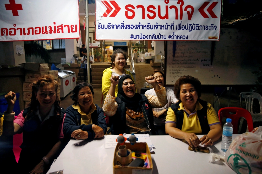 Volunteers celebrate at a press center near Tham Luang cave complex in the northern province of Chiang Rai, Thailand, July 10, 2018. (REUTERS/Soe Zeya Tun)