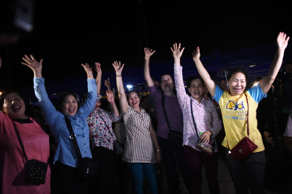 Volunteers celebrate at a makeshift press centre in Mae Sai district of Chiang Rai province on July 10, 2018, after the twelve boys and their football coach were rescued. AFP / Ye Aung Thu