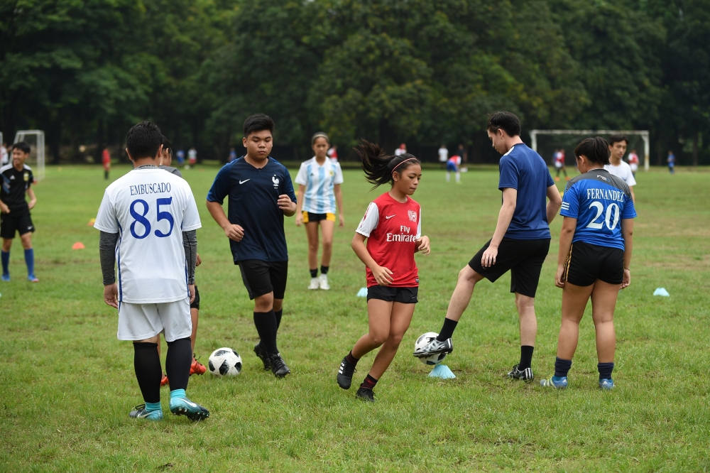 Student football club players training on a school pitch in Manila on June 27, 2018. AFP / Ted Aljibe