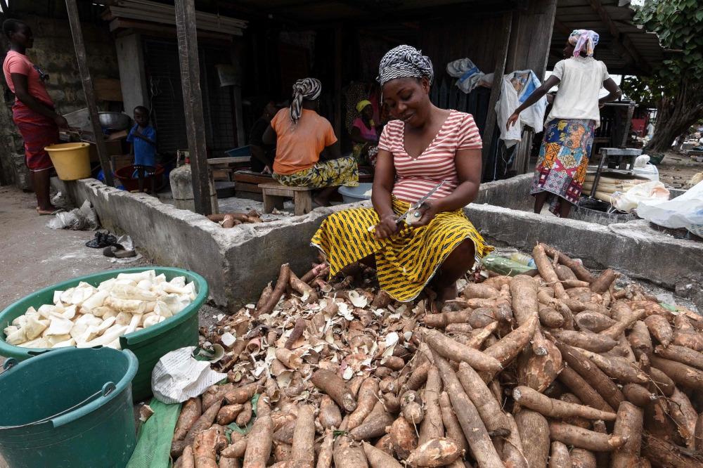 A woman peels outer layers of cassava (manioc) for the attieke side dish in Abidjan, on May 22, 2018.  AFP / Sia Kambou

