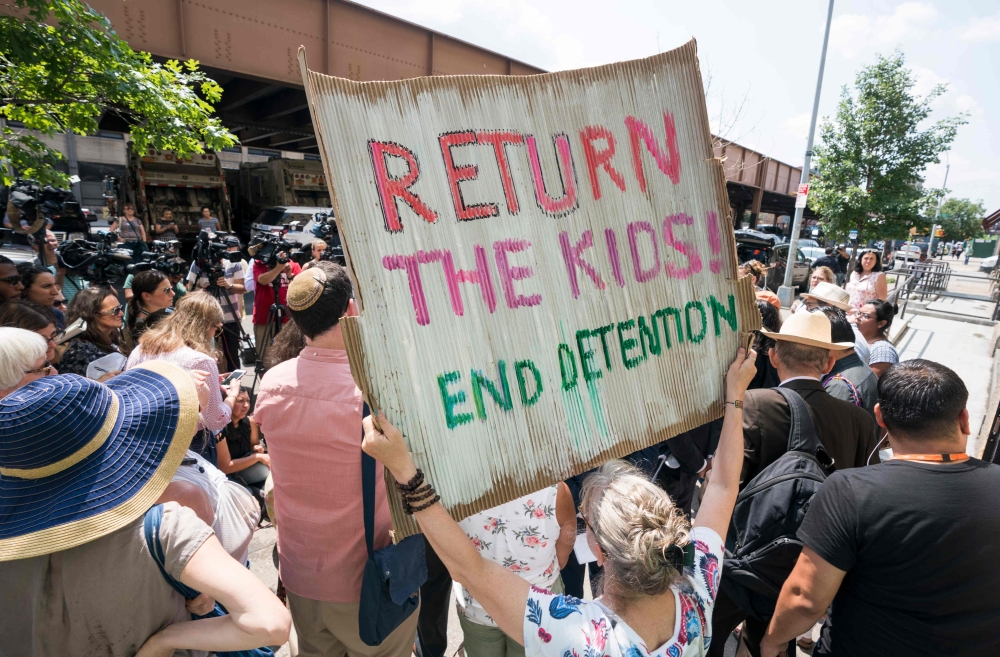 Protesters hold signs as Ravi Ragbir, of the New Sanctuary Coalition, speaks at a press conference to spotlight the impact of the government’s stalling tactics immigrant families on July 11, 2018 in New York.  AFP / Don Emmert  