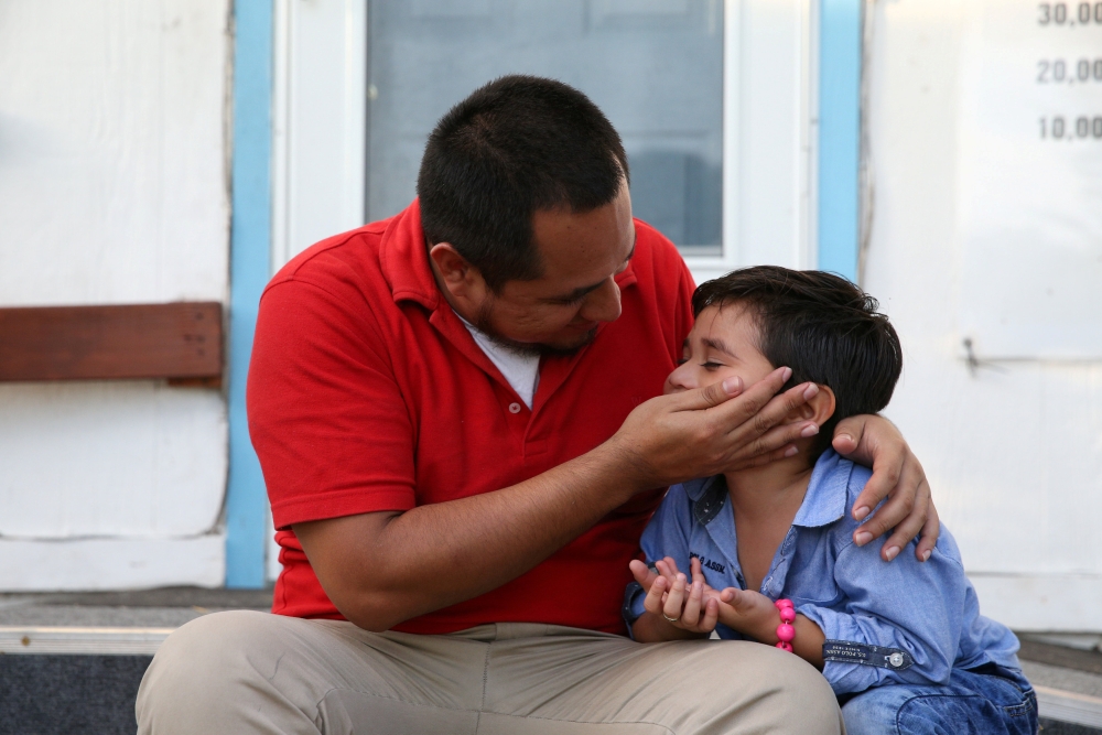 Walter Armando Jimenez Melendez, an asylum seeker from El Salvador, arrives with his four year-old son Jeremy at La Posada Providencia shelter in San Benito, Texas, U.S., shortly after he said they were reunited following separation since late May while i
