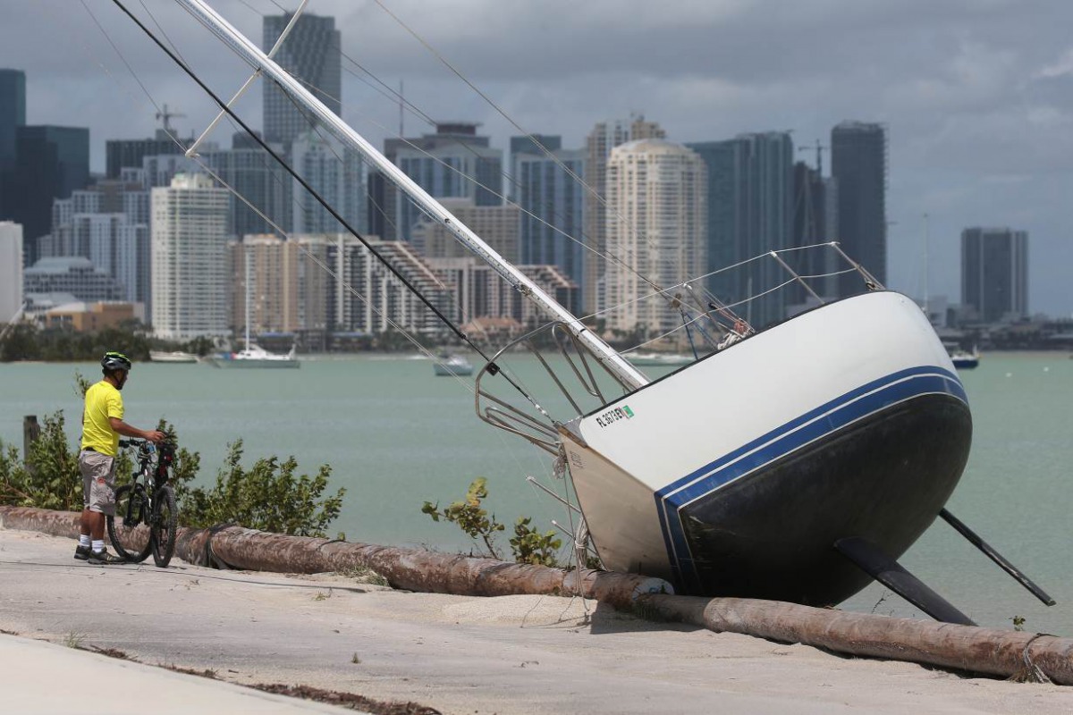A man looks at a boat that has come ashore with the city of Miami in the background following Hurricane Irma in Key Biscayne, Florida, U.S., September 11, 2017. Reuters/Carlo Allegri