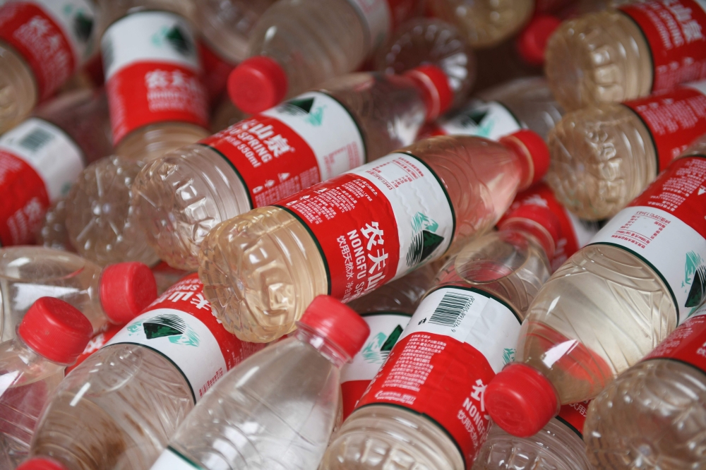 Image of polluted water that has been collected in mineral water bottles at a roving exhibition created by Chinese performance artist Nut Brother, known for his advocacy work on environmental and social issues, in Beijing, July 12, 2018.  / AFP / GREG BAK
