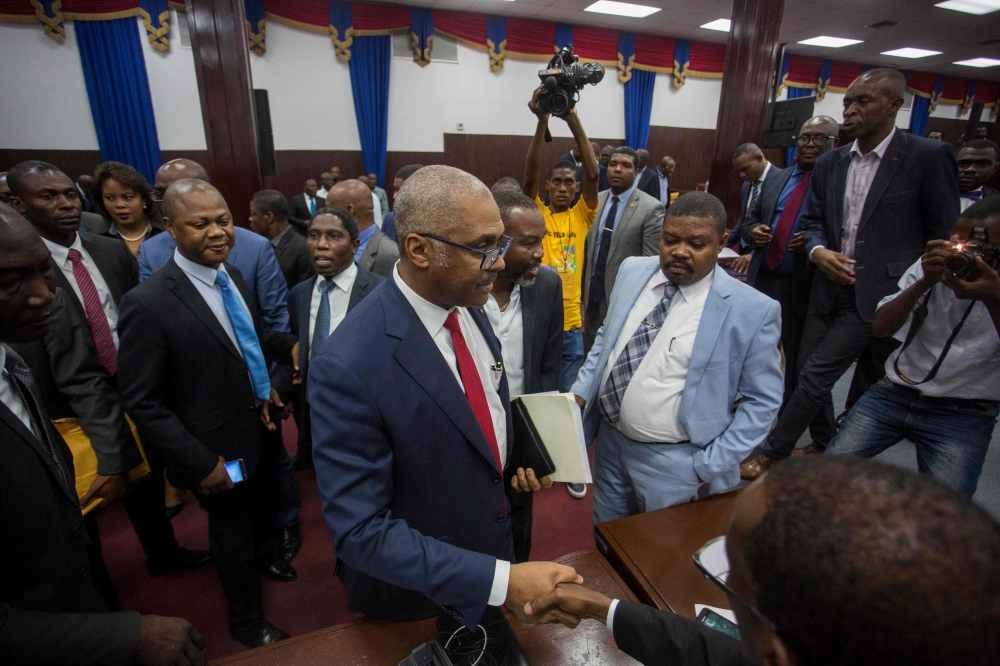 Prime Minister Jack Guy Lafontant greets supporters and opposition alike while leaving the assembly hall after announcing his resignation was accepted earlier in the day on July 14, 2018. AFP / Pierre Michel Jean