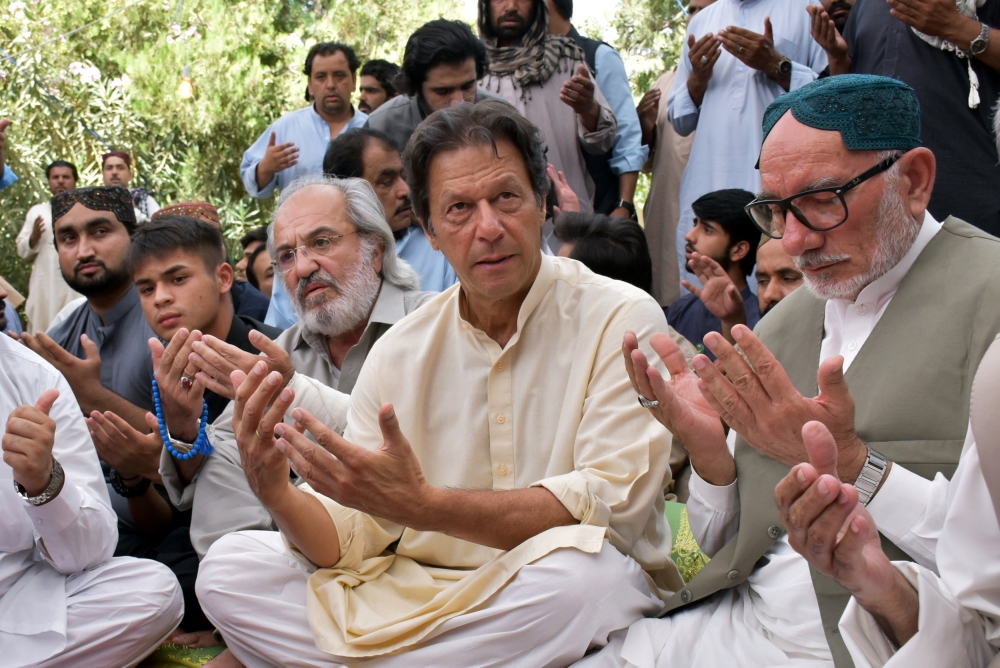 Imran Khan (C), chairman of the Pakistan Tehreek-e-Insaf (PTI), holds his palms to pray and expresses condolence to the relatives of deceased Siraj Raisani, provincial assembly candidate of Baluchistan Awami Party (BAP), who was killed in Friday's suicide