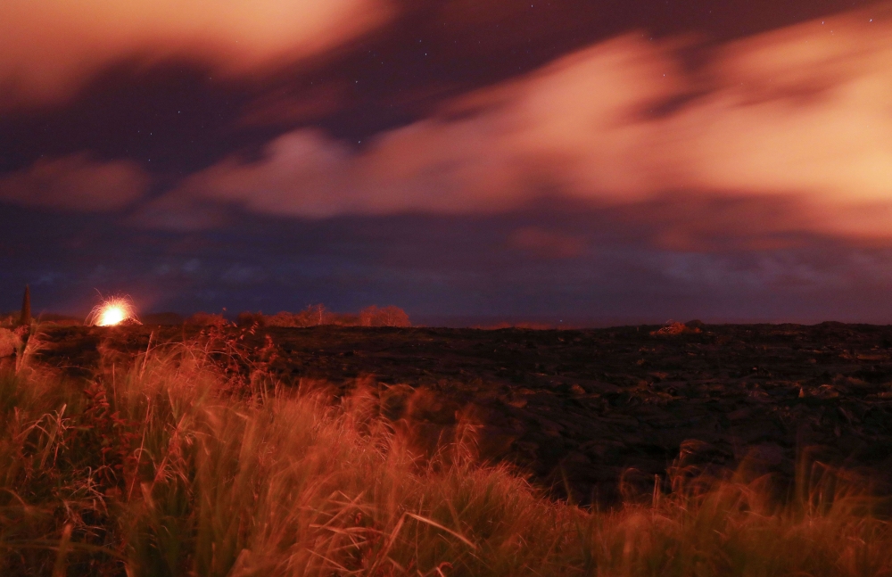 A lava fountain (L) erupts at night along a recent lava flow from a Kilauea volcano fissure on Hawaii's Big Island on May 22, 2018 in Kapoho, Hawaii. Mario Tama/Getty Images/AFP