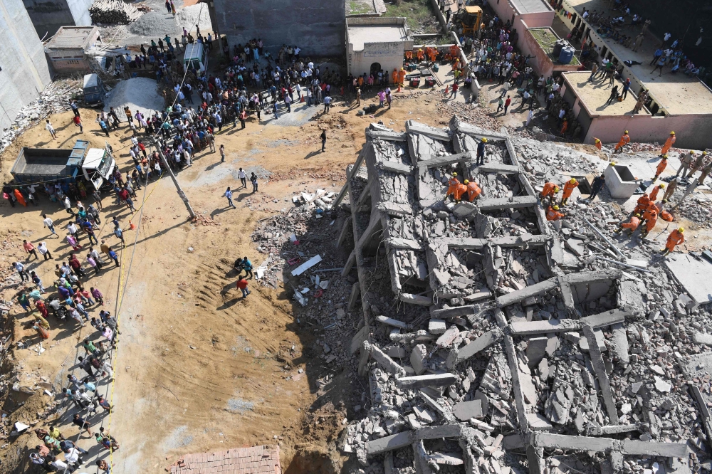  Members of the National Disaster Response Force (NDRF), along with local police, search for victims after an under construction building collapsed in the village of Shah Beri village in Greater Noida, a satellite town east of the Indian capital, in Uttar
