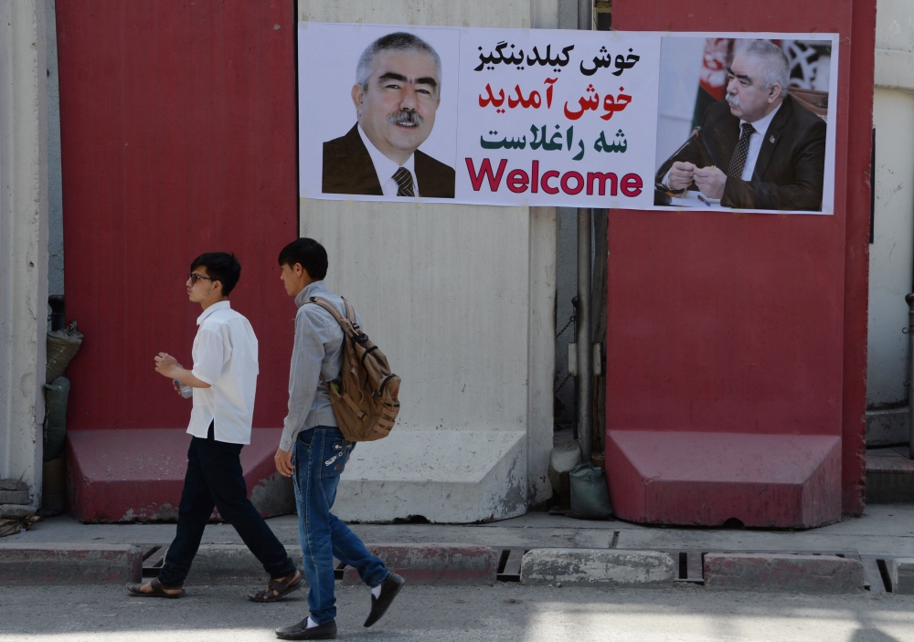 Afghan residents walk past a banner with the image of self-exiled Afghan Vice President Abdul Rashid Dostum ahead of his arrival to Kabul on July 22, 2018. (AFP / NOORULLAH SHIRZADA)