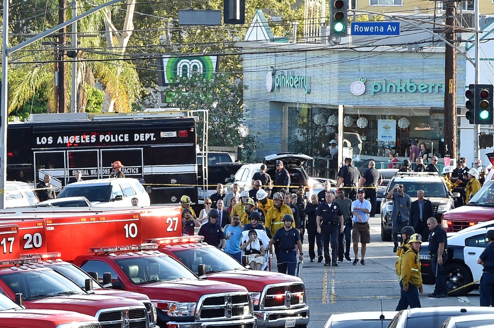 Police officers and members of the Los Angeles Fire Department escort a woman on a stretcher after a suspect barricaded inside a Trader Joe's supermarket in Silverlake, Los Angeles, on July 21, 2018.  AFP / Robyn Beck

