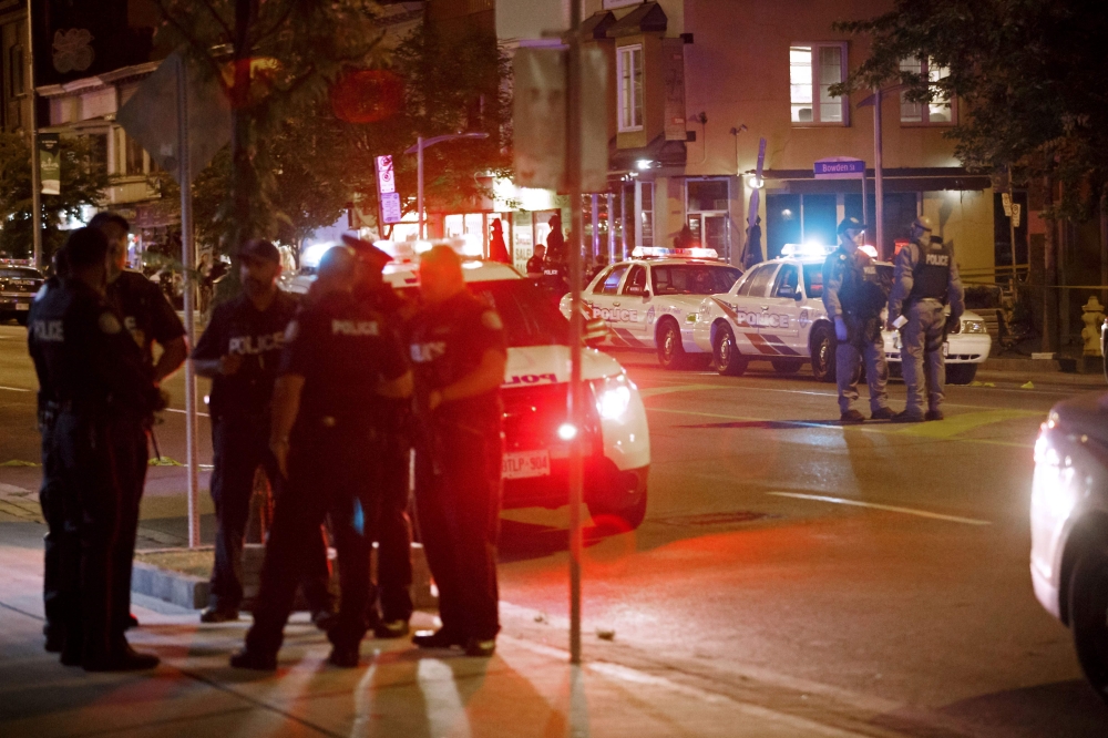 Toronto Police officers walk the scene at Danforth St. at the scene of a shooting in Toronto, Ontario, Canada on Sunday, July 23, 2018. (AFP / Cole BURSTON)