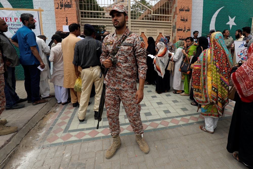 Army soldier stands to guard electoral workers, who gather to collect election materials, ahead of general election in Karachi, Pakistan July 24, 2018. (REUTERS/Akhtar Soomro)