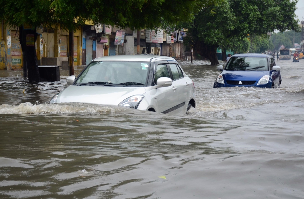 Indian commuters make their way on a flooded road following heavy rain in Mathura in India's Uttar Pradesh state on July 26, 2018. (AFP)