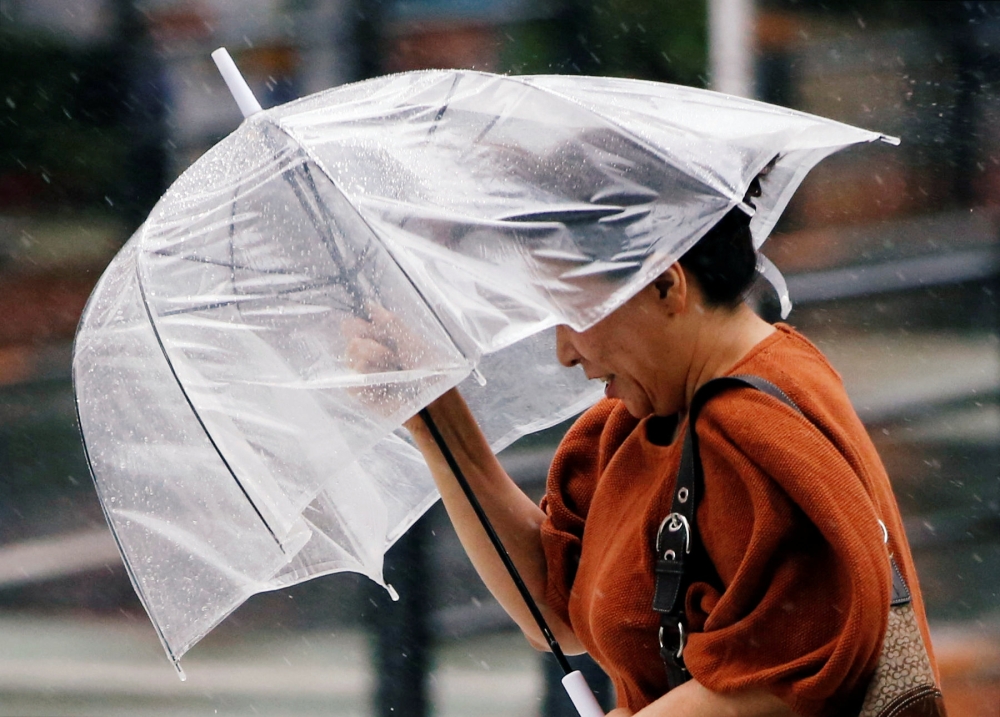 A passerby using an umbrella struggles against a heavy rain and wind as Typhoon Jongdari approaches Japan's mainland in Tokyo, Japan July 28, 2018. Reuters/Issei Kato
