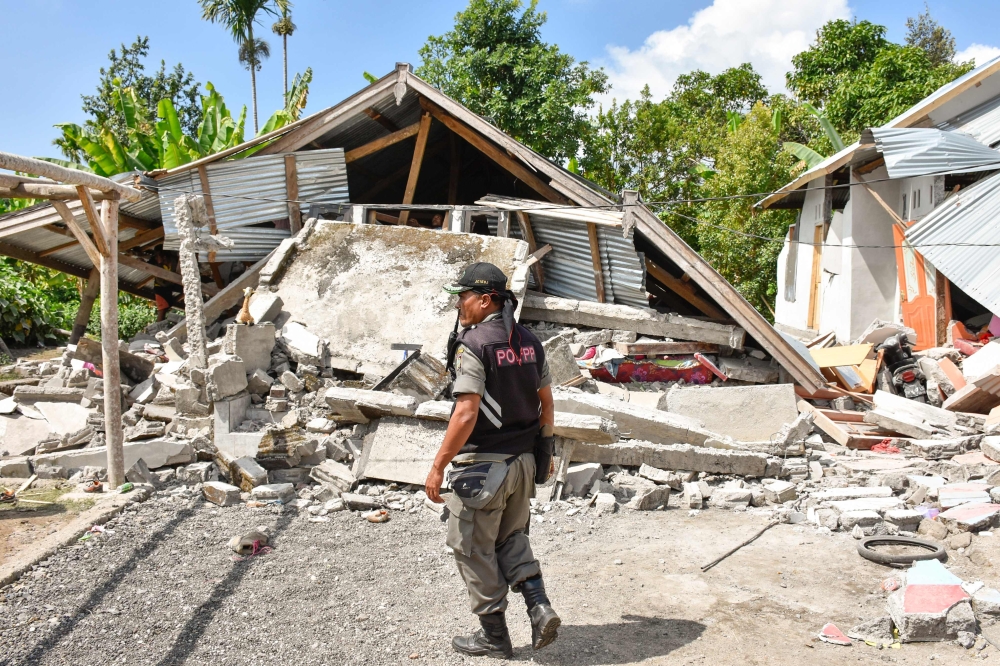 An Indonesian village security officer examines the remains of houses, after a 6.4 magnitude earthquake struck, in Lombok on July 29, 2018. (AFP / Aulia AHMAD)