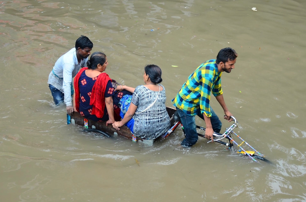 In this file photo taken on July 26, 2018 Indian women are transported on a bicycle cart on a flooded road following heavy rain in Mathura in India's Uttar Pradesh state Heavy monsoon rains that sparked floods and caused buildings to collapse. AFP